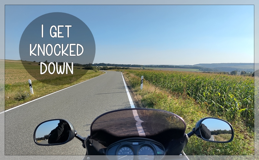 Headerbild: Motorrad-Cockpit im Vordergrund, einsame Landstraße mit blauem Himmel im Hintergrund