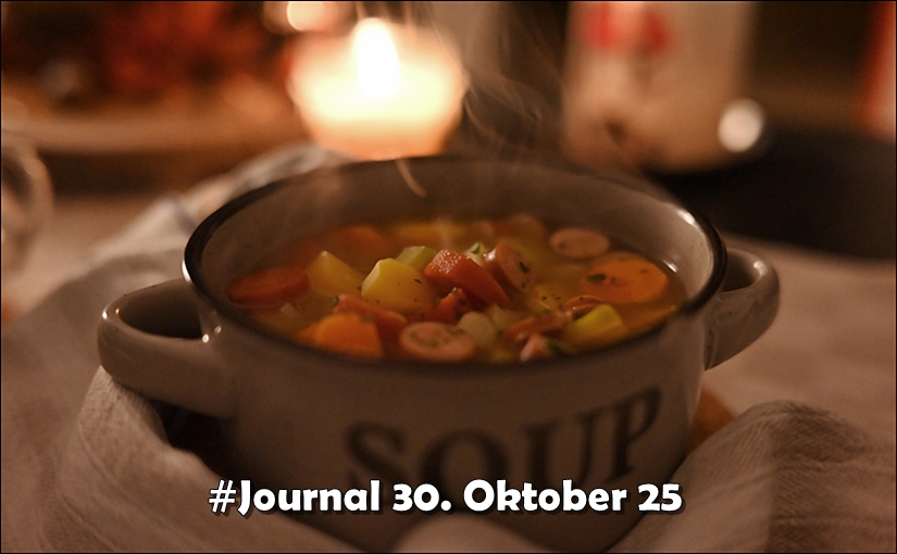 Schale mit Suppe (Möhreneintopf) auf einer zerknüllten Serviette, dunkel, mit Kerzenlicht im Hintergrund