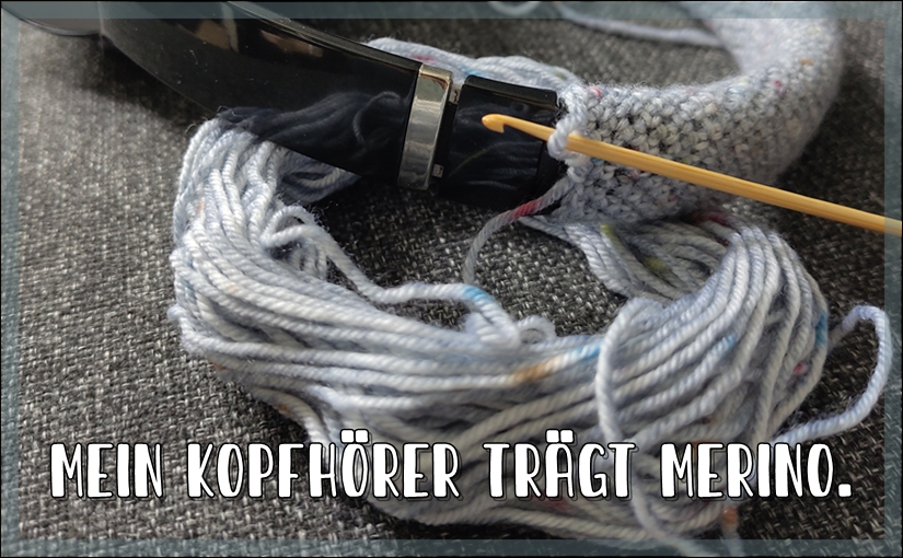 Kopfhörerbügel umhäkelt, im Vordergrund ein Wollrest und eine Häkelnadel